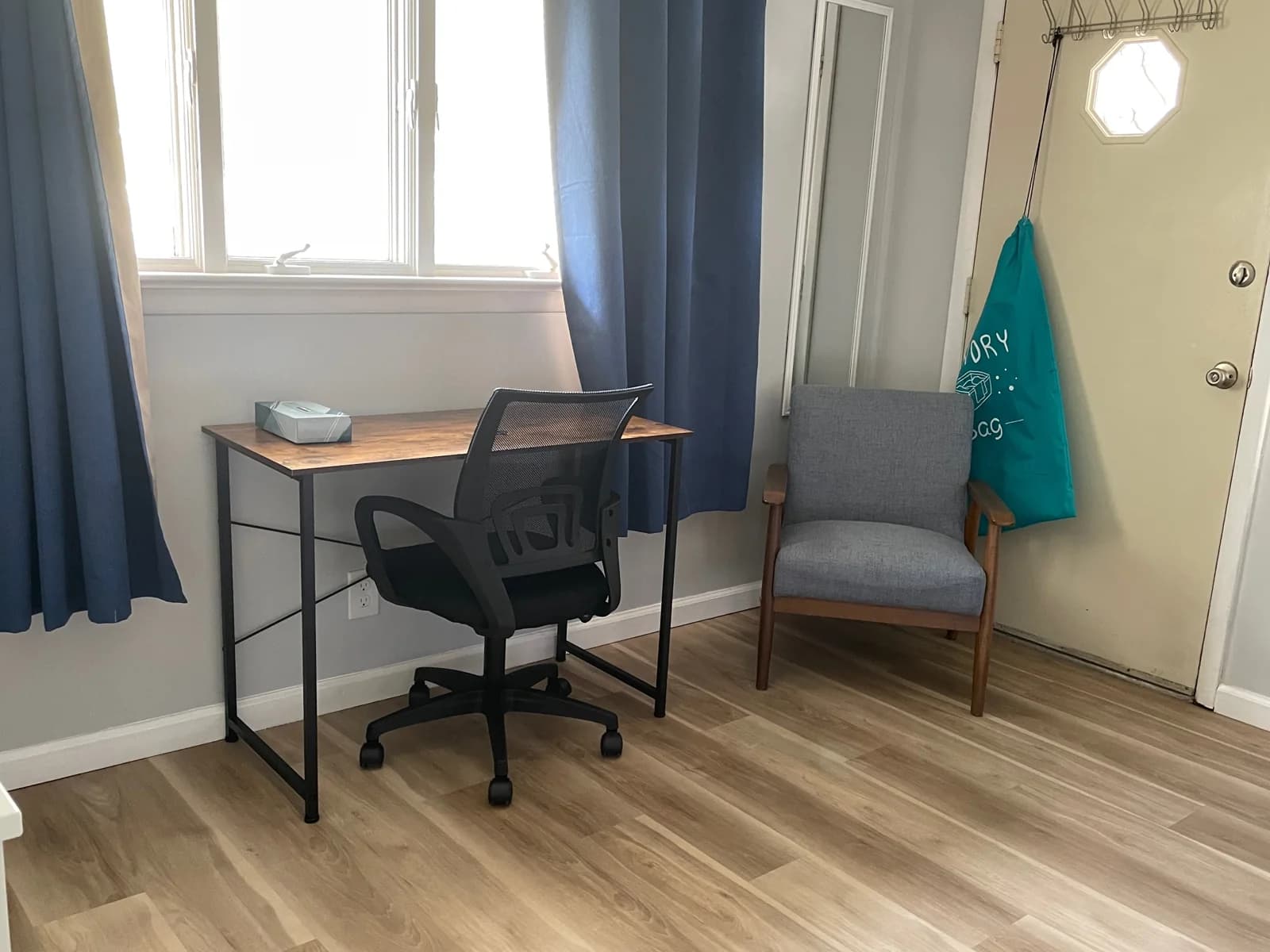 Desk and office chair beside a window with blue curtains.
