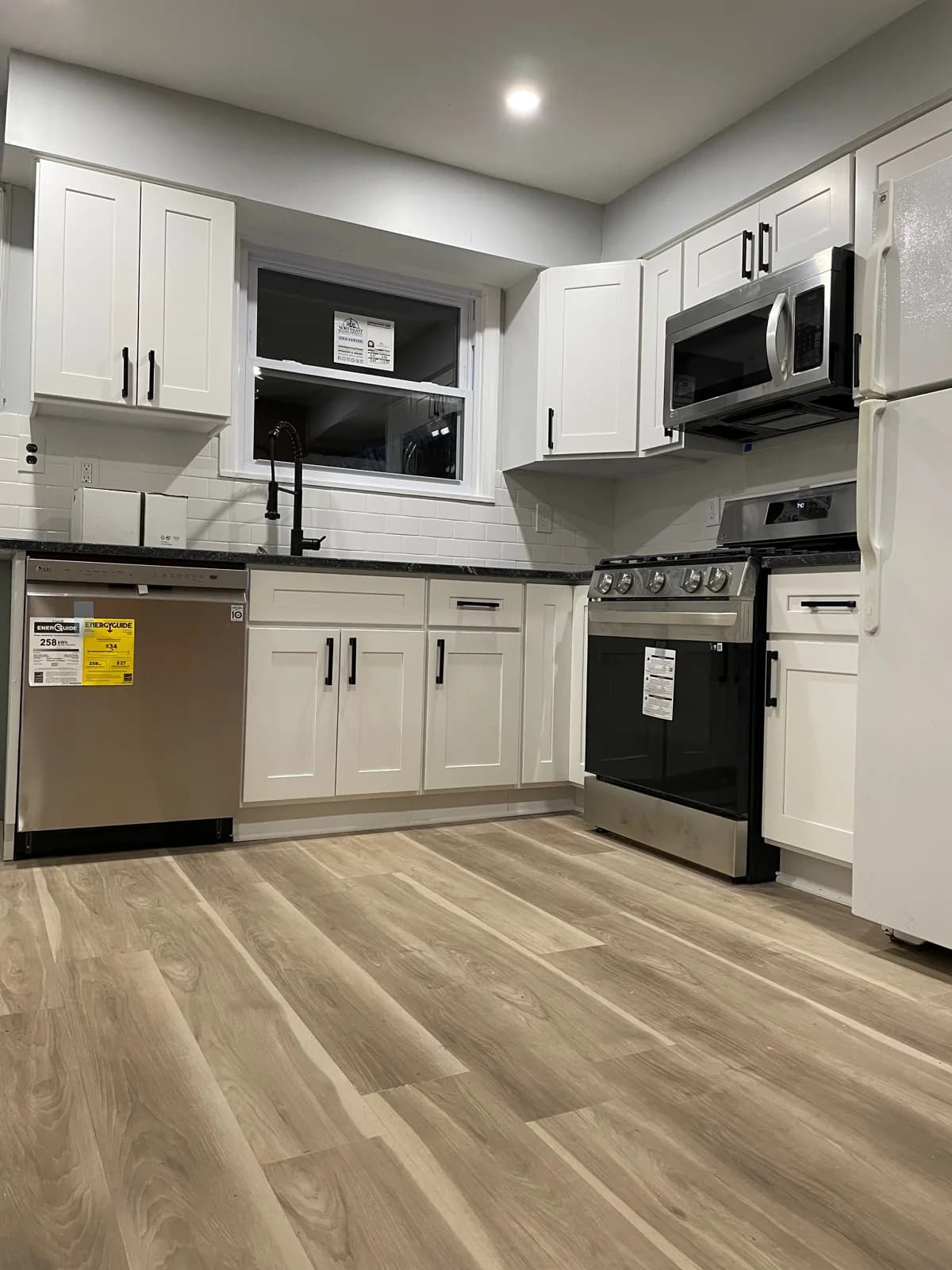 Kitchen with white cabinets, a stove, microwave, sink, and dishwasher.