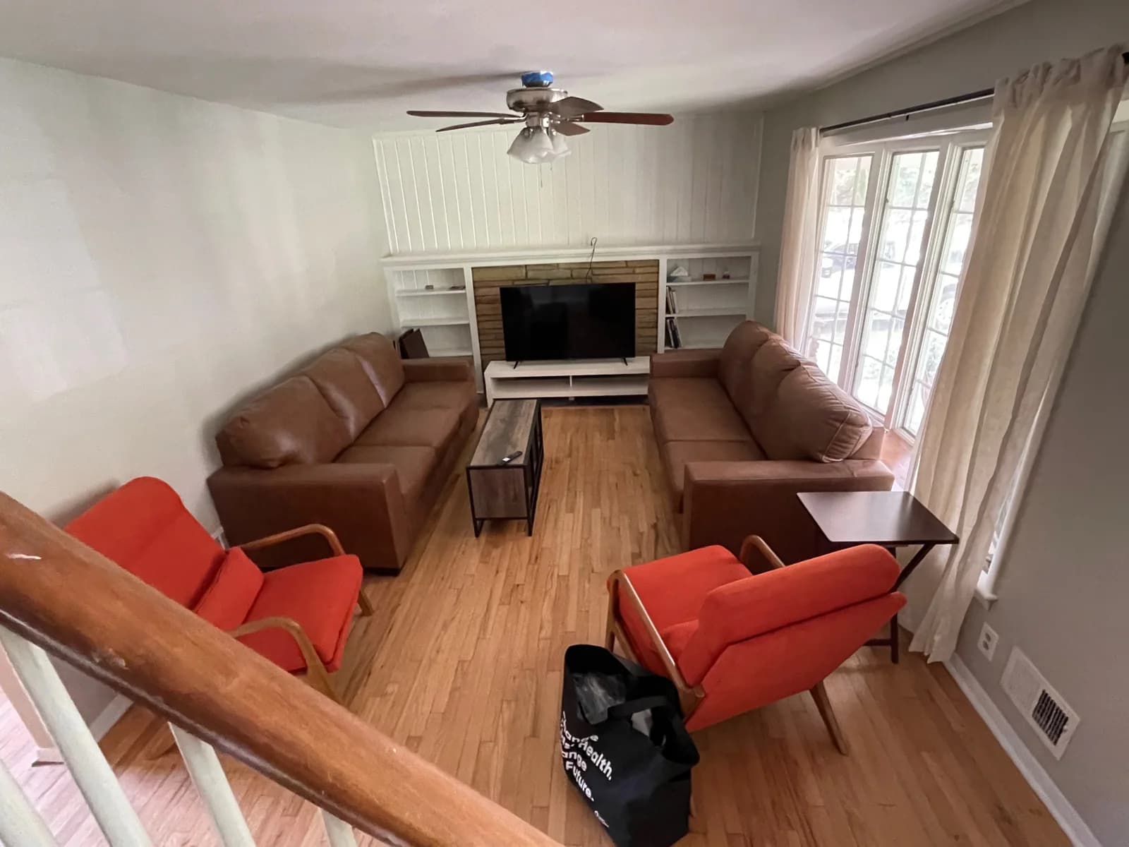 Living room with two sofas, red chairs, and a television.